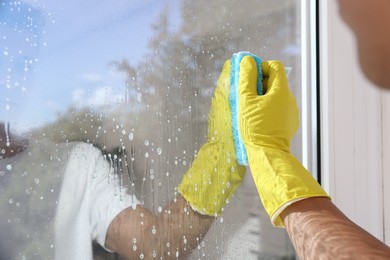 Photo of Man cleaning window with rag indoors, closeup