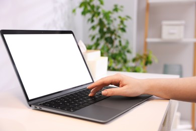 Photo of Woman working with laptop at white table indoors, closeup. Mockup for design