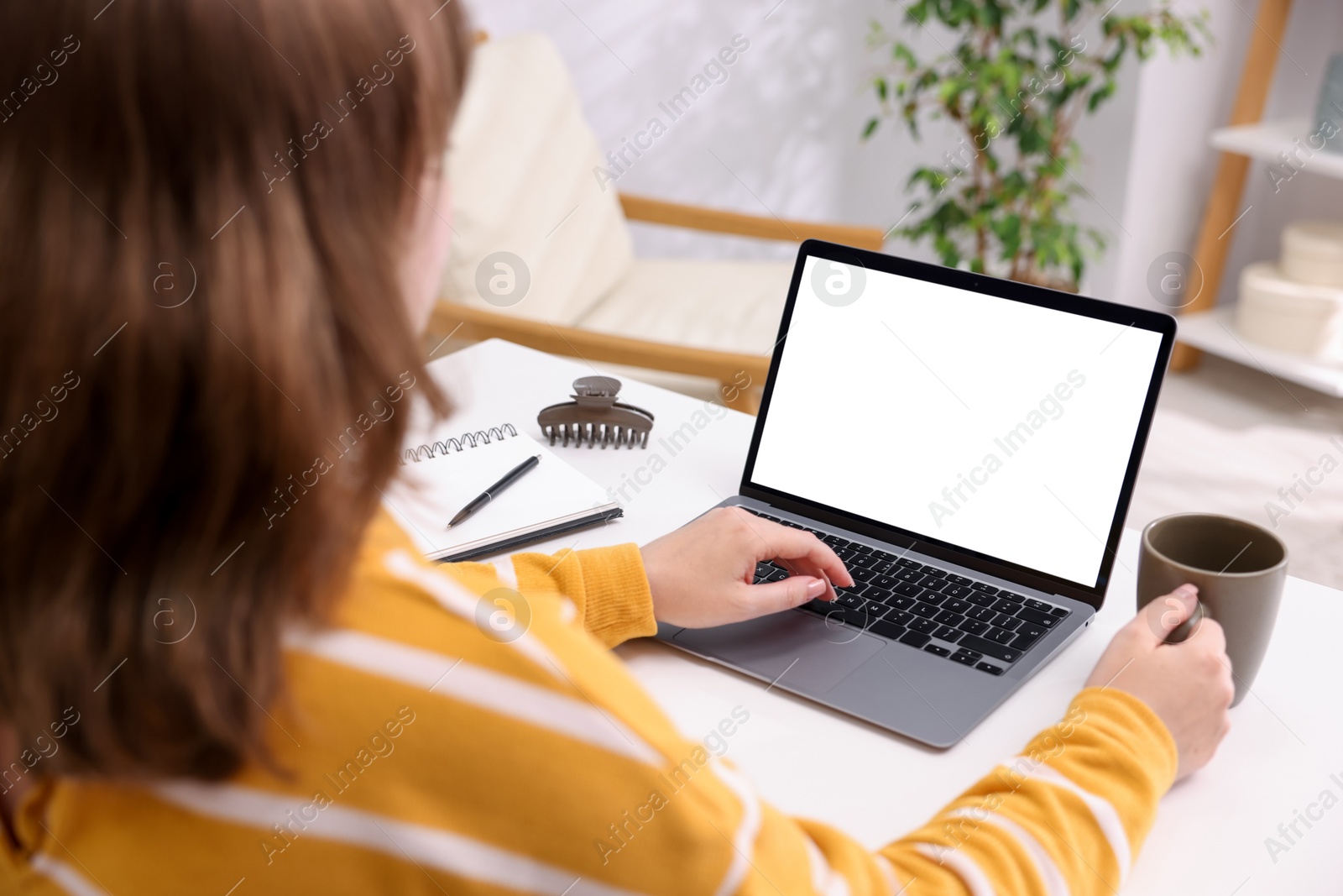 Photo of Woman working with laptop at white table indoors, closeup. Mockup for design