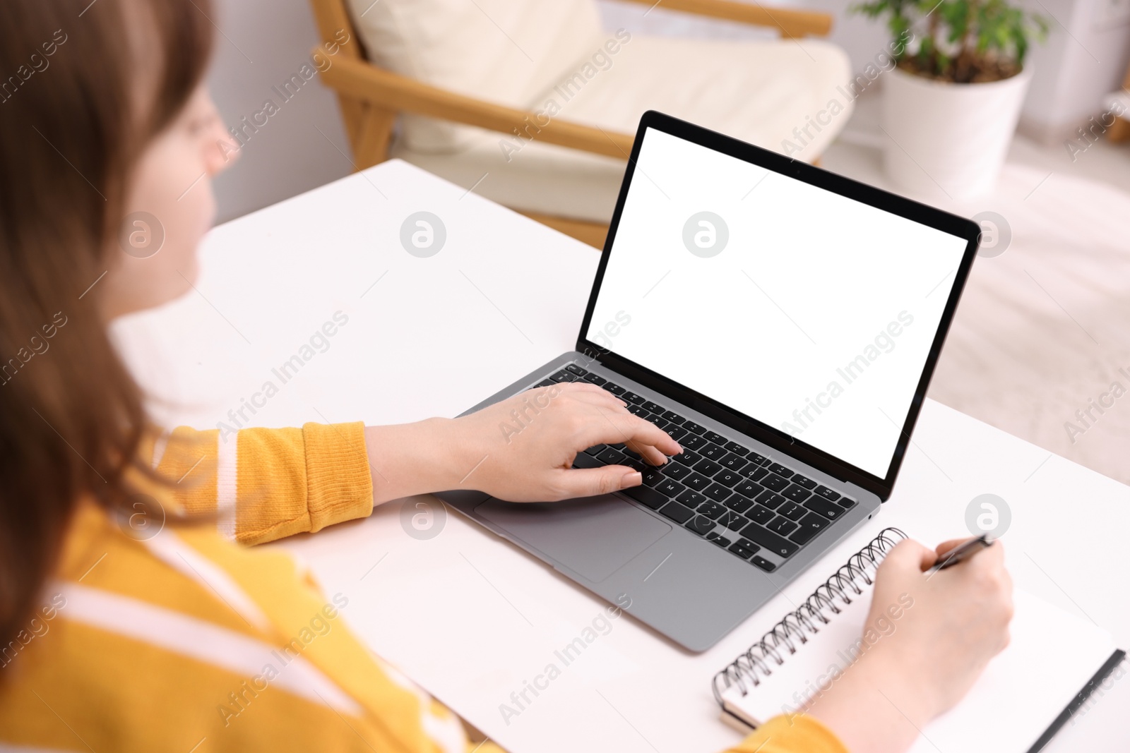 Photo of Woman working with laptop at white table indoors, closeup. Mockup for design