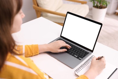 Photo of Woman working with laptop at white table indoors, closeup. Mockup for design
