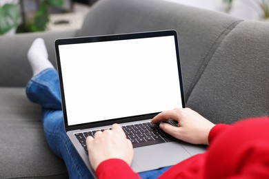 Photo of Woman working with laptop on sofa indoors, closeup. Mockup for design