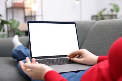Photo of Woman working with laptop on sofa indoors, closeup. Mockup for design
