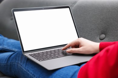 Photo of Woman working with laptop on sofa indoors, closeup. Mockup for design