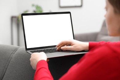 Photo of Woman working with laptop on sofa indoors, closeup. Mockup for design
