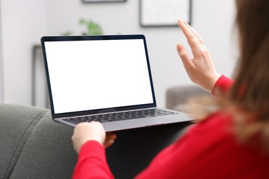 Photo of Woman working with laptop on sofa indoors, closeup. Mockup for design