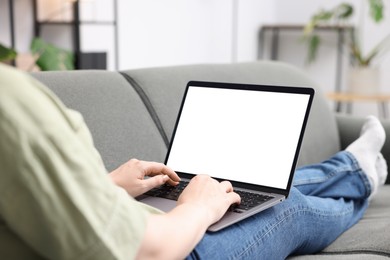 Photo of Woman working with laptop on sofa indoors, closeup. Mockup for design
