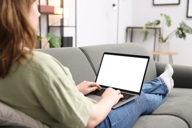 Photo of Woman working with laptop on sofa indoors, closeup. Mockup for design