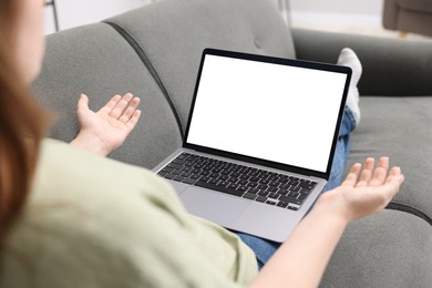 Photo of Woman working with laptop on sofa indoors, closeup. Mockup for design