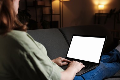 Photo of Woman working with laptop on sofa indoors, closeup. Mockup for design