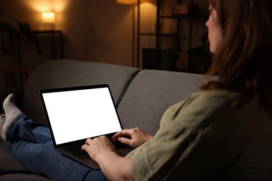 Photo of Woman working with laptop on sofa indoors, closeup. Mockup for design