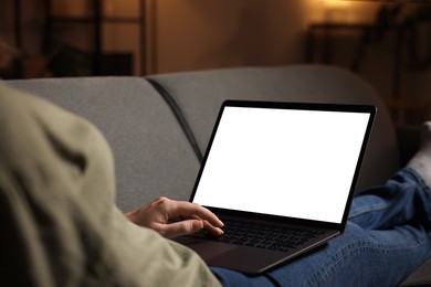 Photo of Woman working with laptop on sofa indoors, closeup. Mockup for design