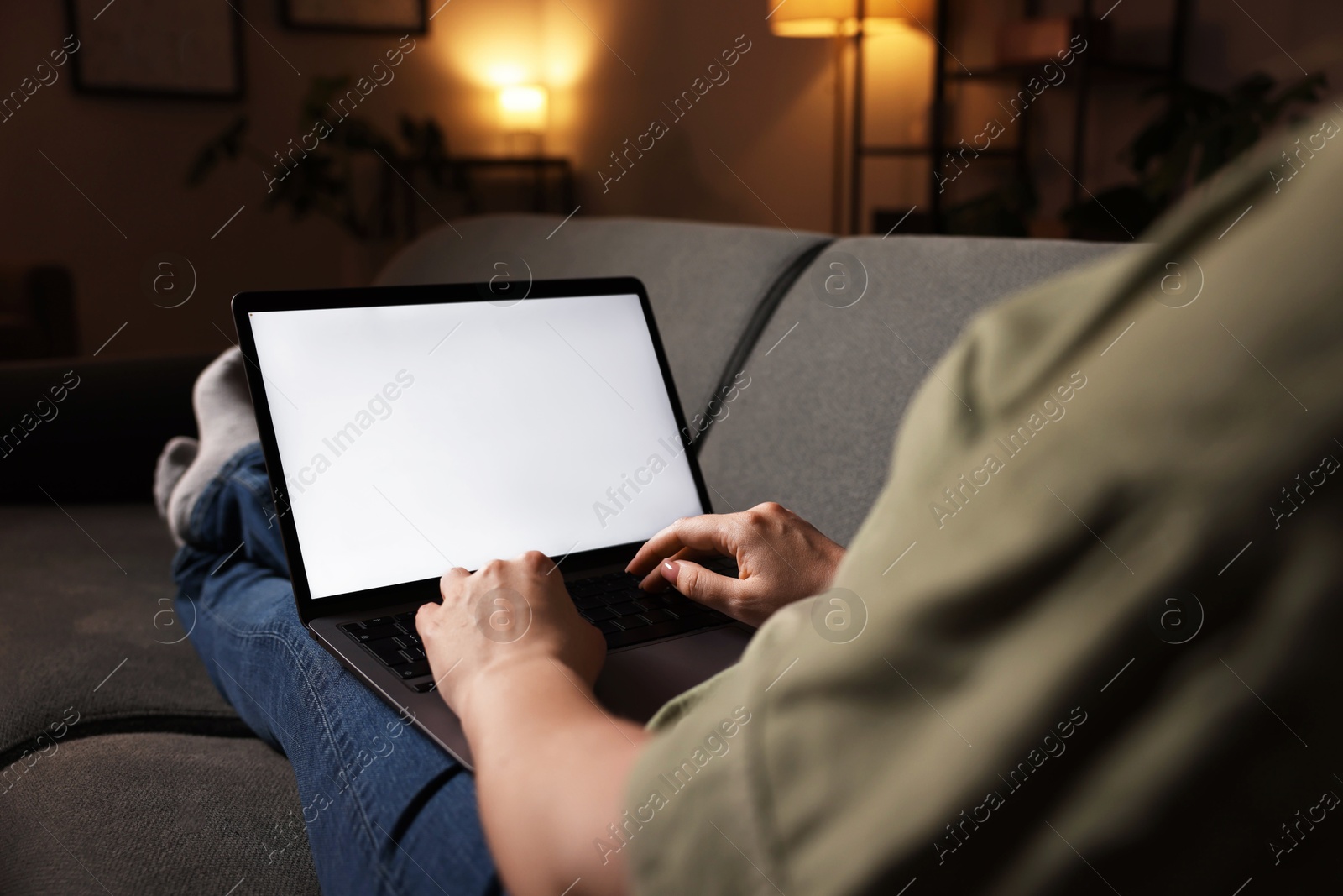 Photo of Woman working with laptop on sofa indoors, closeup. Mockup for design