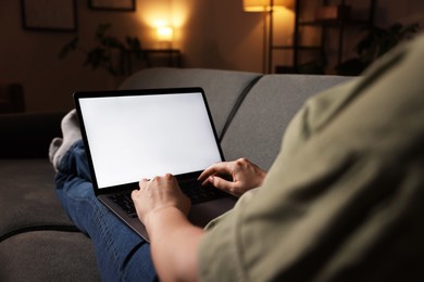 Photo of Woman working with laptop on sofa indoors, closeup. Mockup for design