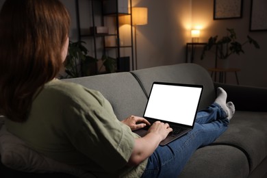 Photo of Woman working with laptop on sofa indoors, closeup. Mockup for design