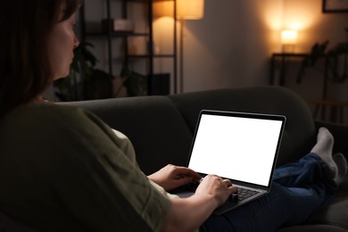 Photo of Woman working with laptop on sofa indoors, closeup. Mockup for design