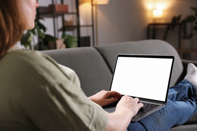 Photo of Woman working with laptop on sofa indoors, closeup. Mockup for design