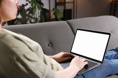 Photo of Woman working with laptop on sofa indoors, closeup. Mockup for design