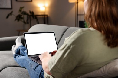 Photo of Woman working with laptop on sofa indoors, closeup. Mockup for design