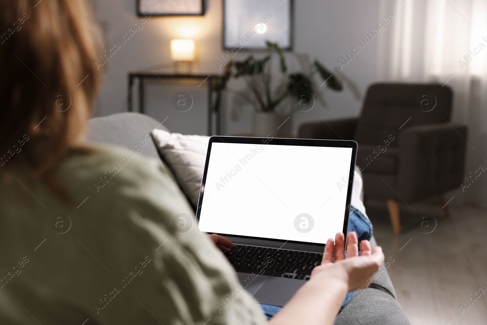Photo of Woman working with laptop on sofa indoors, closeup. Mockup for design