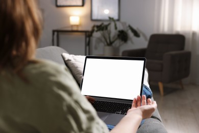 Photo of Woman working with laptop on sofa indoors, closeup. Mockup for design
