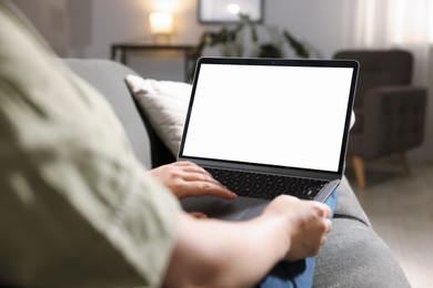Photo of Woman working with laptop on sofa indoors, closeup. Mockup for design
