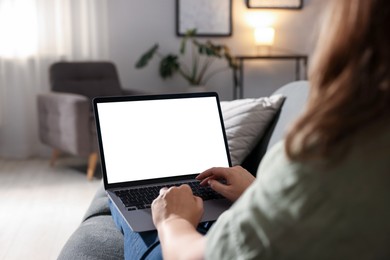 Photo of Woman working with laptop on sofa indoors, closeup. Mockup for design