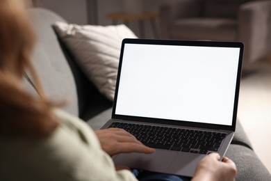 Photo of Woman working with laptop on sofa indoors, closeup. Mockup for design