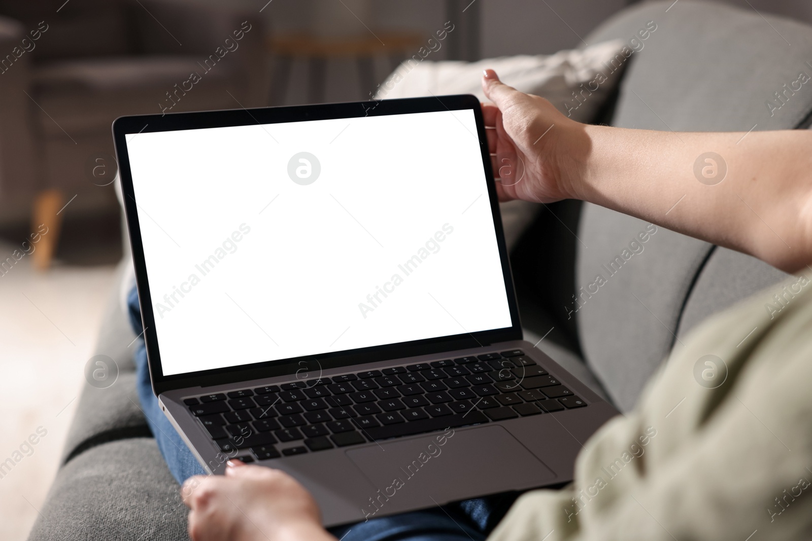 Photo of Woman working with laptop on sofa indoors, closeup. Mockup for design