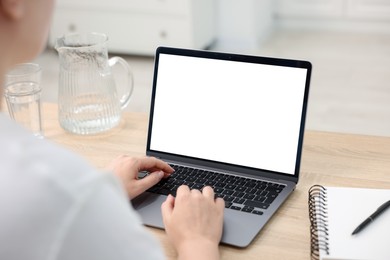 Photo of Woman working with laptop at wooden table indoors, closeup. Mockup for design