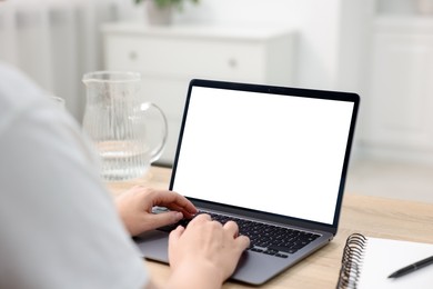 Photo of Woman working with laptop at wooden table indoors, closeup. Mockup for design