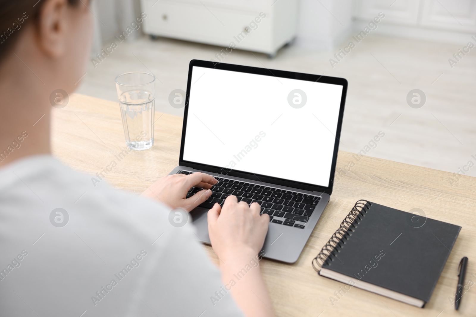 Photo of Woman working with laptop at wooden table indoors, closeup. Mockup for design