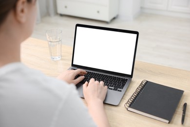 Photo of Woman working with laptop at wooden table indoors, closeup. Mockup for design