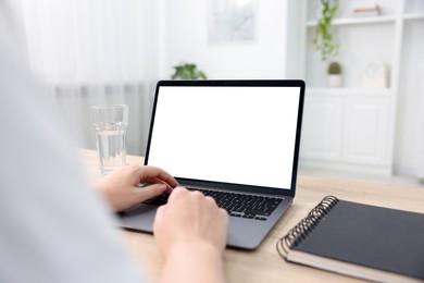 Photo of Woman working with laptop at wooden table indoors, closeup. Mockup for design