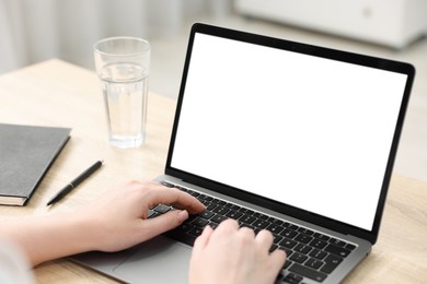 Photo of Woman working with laptop at wooden table indoors, closeup. Mockup for design