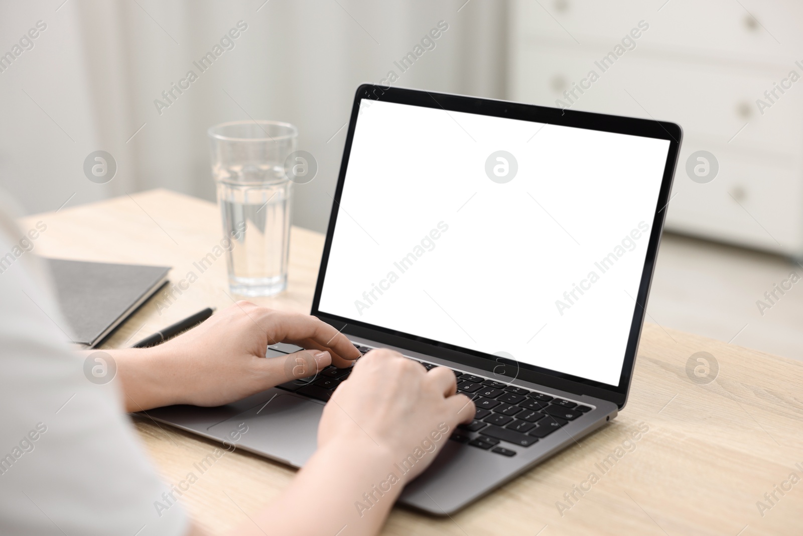 Photo of Woman working with laptop at wooden table indoors, closeup. Mockup for design
