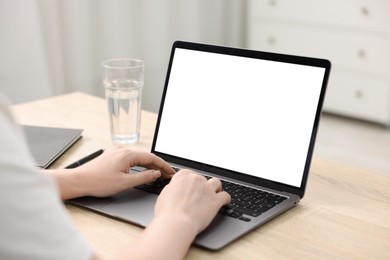 Photo of Woman working with laptop at wooden table indoors, closeup. Mockup for design