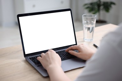 Photo of Woman working with laptop at wooden table indoors, closeup. Mockup for design