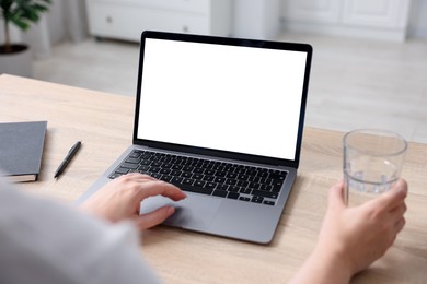 Photo of Woman working with laptop at wooden table indoors, closeup. Mockup for design