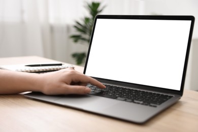 Photo of Woman working with laptop at wooden table indoors, closeup. Mockup for design