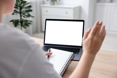 Photo of Woman working with laptop at wooden table indoors, closeup. Mockup for design