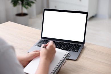 Photo of Woman working with laptop at wooden table indoors, closeup. Mockup for design