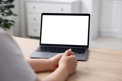 Photo of Woman working with laptop at wooden table indoors, closeup. Mockup for design
