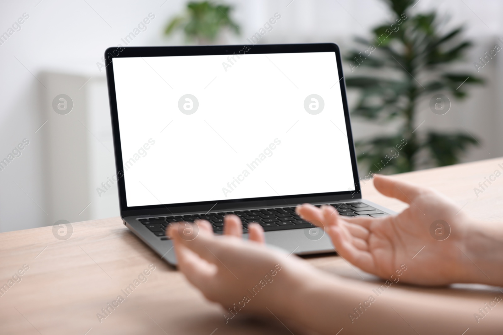 Photo of Woman working with laptop at wooden table indoors, closeup. Mockup for design