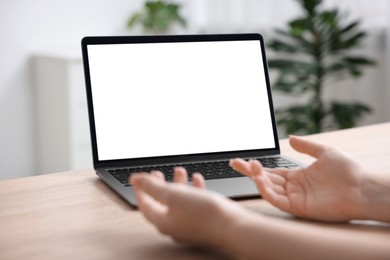 Photo of Woman working with laptop at wooden table indoors, closeup. Mockup for design