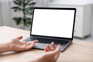 Photo of Woman working with laptop at wooden table indoors, closeup. Mockup for design