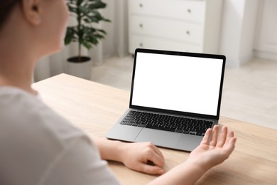Photo of Woman working with laptop at wooden table indoors, closeup. Mockup for design