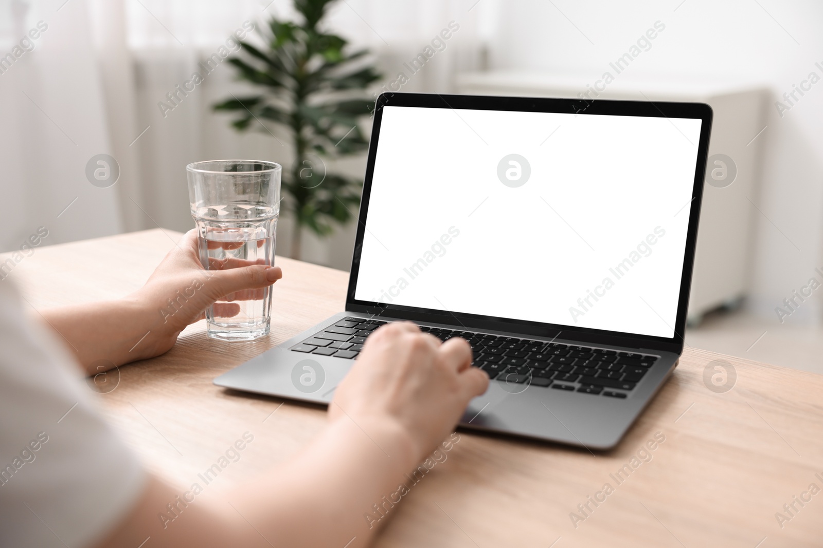 Photo of Woman working with laptop at wooden table indoors, closeup. Mockup for design