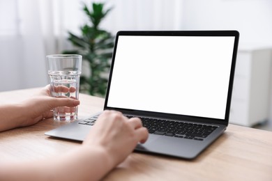 Photo of Woman working with laptop at wooden table indoors, closeup. Mockup for design