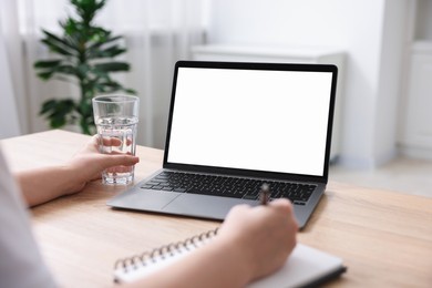 Photo of Woman working with laptop at wooden table indoors, closeup. Mockup for design